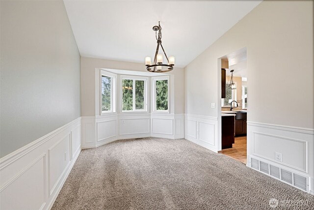 unfurnished room featuring visible vents, lofted ceiling, a sink, light carpet, and a chandelier