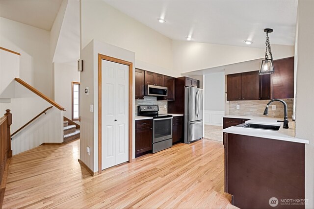 kitchen featuring light wood finished floors, dark brown cabinets, stainless steel appliances, and a sink