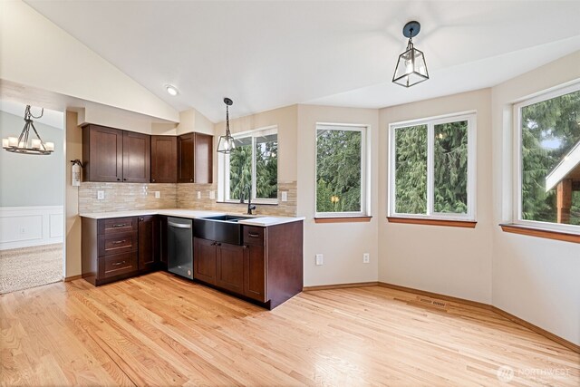 kitchen featuring dark brown cabinetry, light countertops, lofted ceiling, and a sink