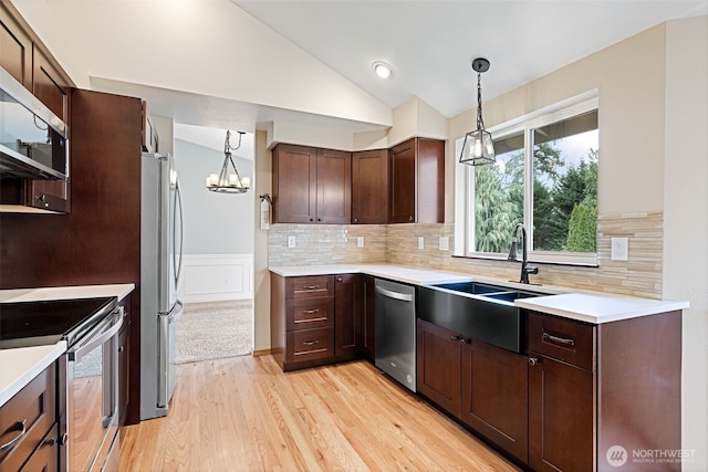 kitchen featuring vaulted ceiling, light countertops, appliances with stainless steel finishes, and a sink