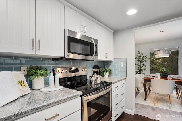 kitchen with light stone counters, dark wood finished floors, stainless steel appliances, white cabinets, and backsplash