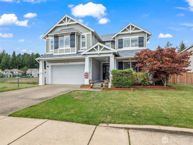 craftsman-style home featuring a front lawn, fence, a garage, and driveway