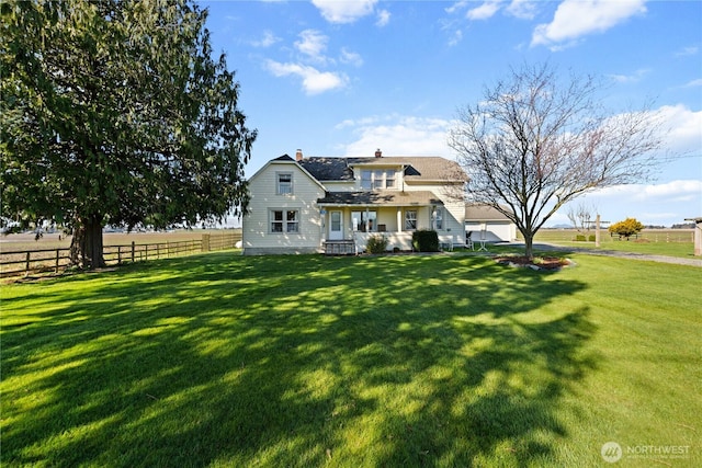 view of front facade with a chimney, a front lawn, and fence