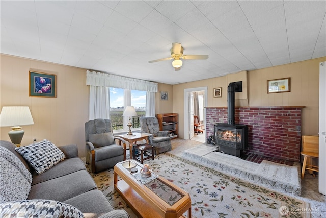 living area with a wood stove and a ceiling fan