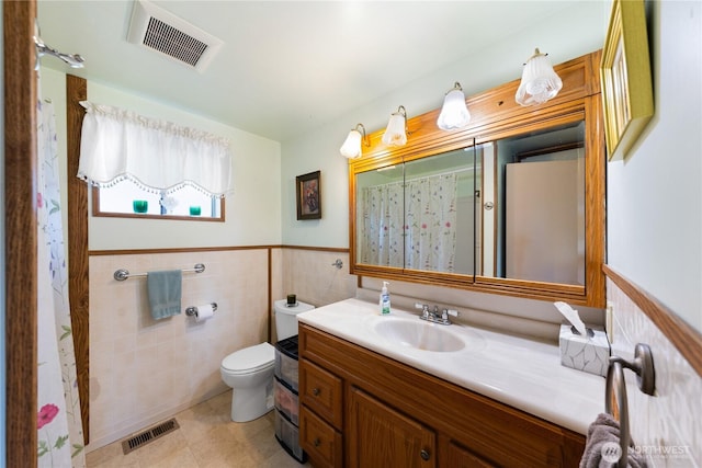 bathroom with vanity, tile walls, visible vents, and wainscoting