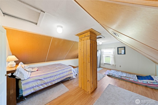 bedroom featuring vaulted ceiling, attic access, and wood finished floors