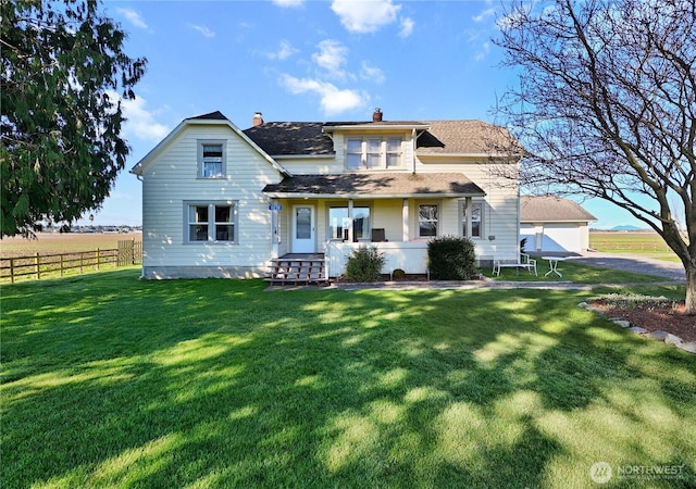 rear view of house featuring a detached garage, fence, a yard, covered porch, and a chimney