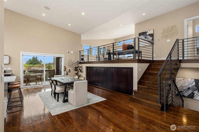 dining room featuring stairway, recessed lighting, a towering ceiling, and hardwood / wood-style flooring