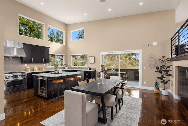 dining area featuring dark wood-style floors, beverage cooler, baseboards, and a wealth of natural light