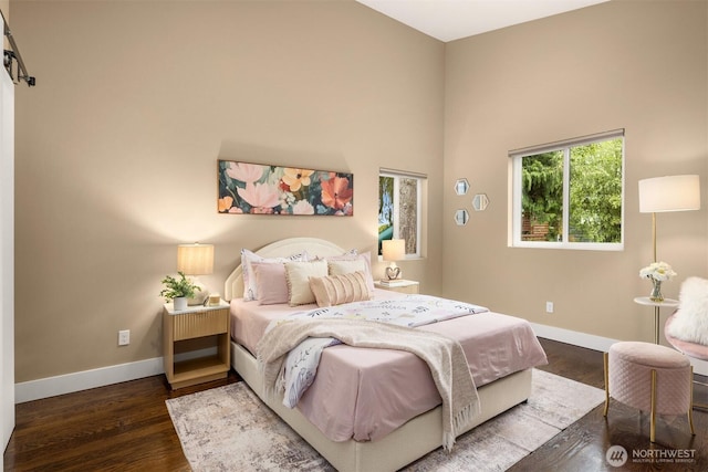 bedroom featuring a high ceiling, baseboards, and wood finished floors