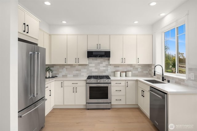 kitchen with tasteful backsplash, light wood-style flooring, stainless steel appliances, and a sink