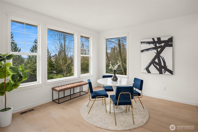 dining room with wood finished floors, visible vents, a wealth of natural light, and baseboards