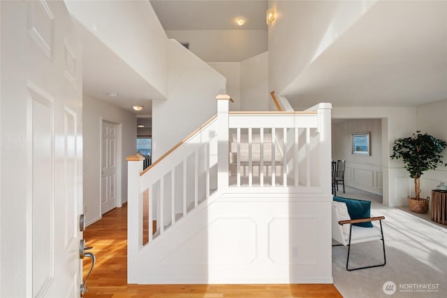 stairs with wood finished floors and a decorative wall