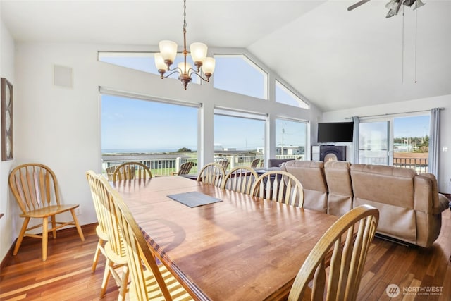 dining room featuring ceiling fan with notable chandelier, vaulted ceiling, wood finished floors, and visible vents