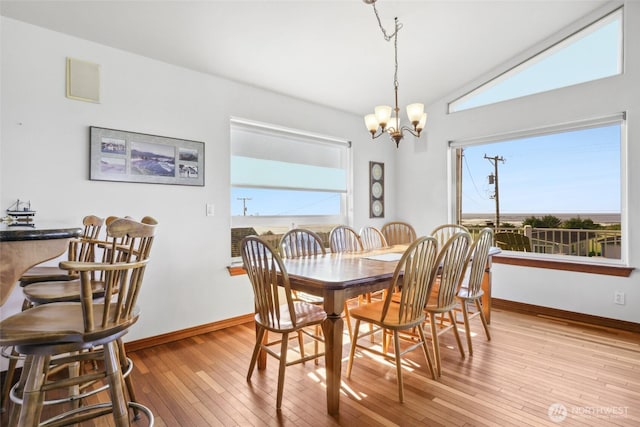 dining area featuring hardwood / wood-style floors, lofted ceiling, a notable chandelier, and baseboards