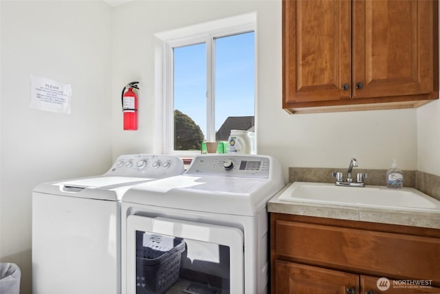 clothes washing area featuring cabinet space, independent washer and dryer, and a sink