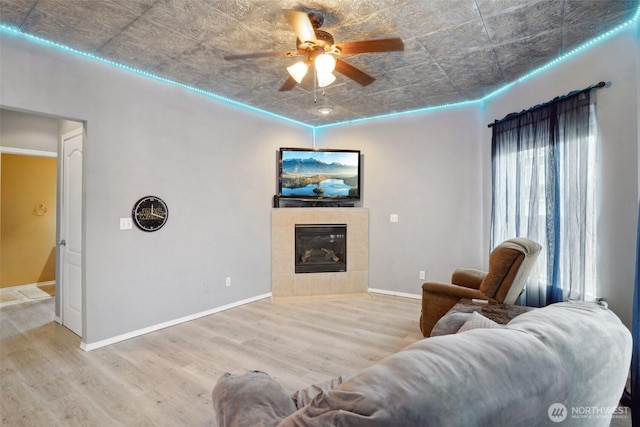 living area featuring baseboards, an ornate ceiling, wood finished floors, and a tile fireplace