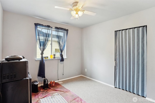 interior space with baseboards, carpet floors, and a ceiling fan