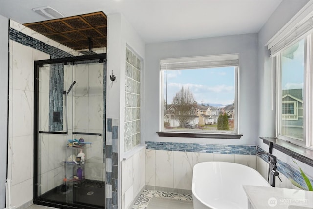 bathroom featuring a soaking tub, a stall shower, tile walls, and visible vents