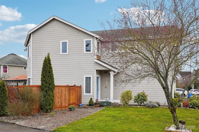 traditional-style home featuring a front lawn and fence