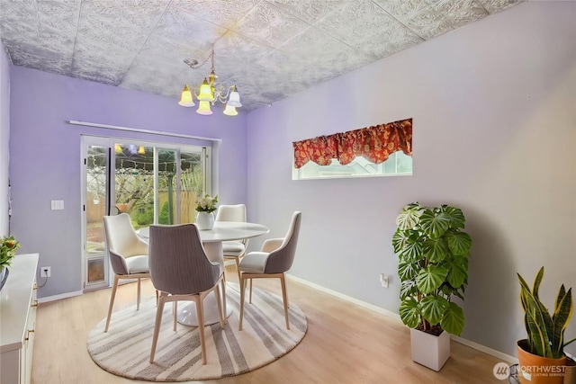 dining area with baseboards, an inviting chandelier, and light wood finished floors