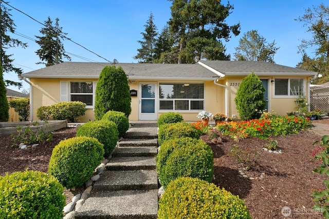 ranch-style house featuring stucco siding and fence