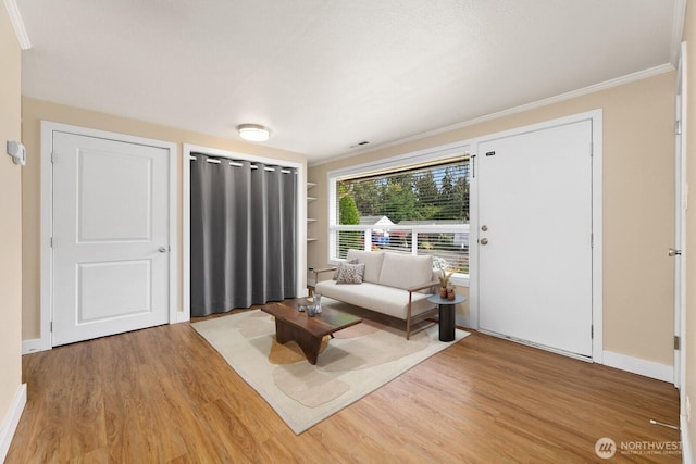 living area with visible vents, crown molding, baseboards, and wood finished floors