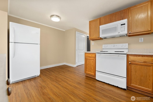 kitchen with white appliances, light countertops, and light wood finished floors