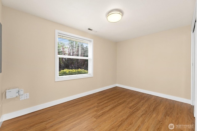 empty room featuring visible vents, baseboards, and wood finished floors