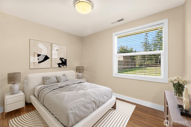 bedroom featuring visible vents, baseboards, and wood finished floors