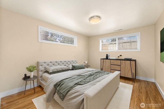 bedroom with light wood-style floors, visible vents, and baseboards