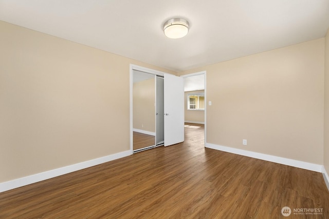 spare room featuring baseboards and wood finished floors