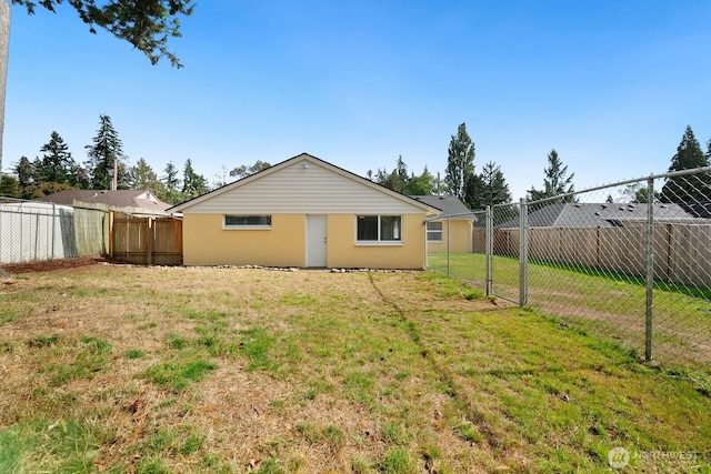 back of house with a lawn and a fenced backyard