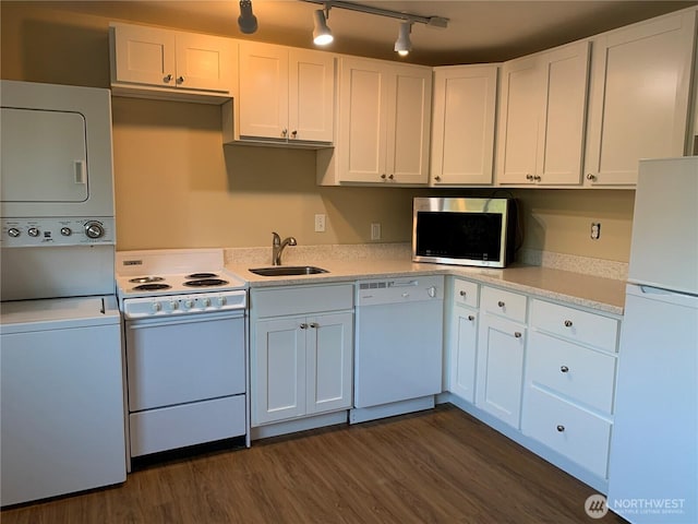 kitchen with white appliances, dark wood-style floors, stacked washing maching and dryer, a sink, and white cabinetry