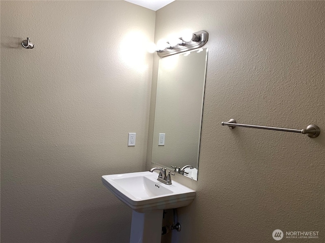 bathroom featuring a textured wall and a sink