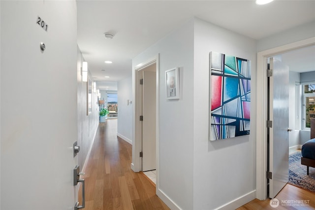 hallway with light wood-type flooring and baseboards