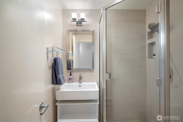 full bath featuring decorative backsplash, a shower stall, and a sink