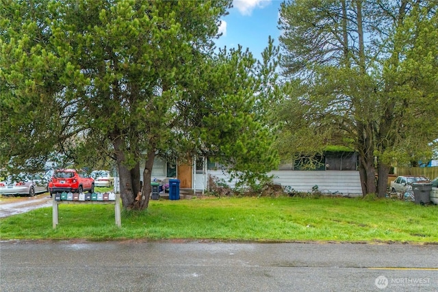 view of property hidden behind natural elements featuring a front yard