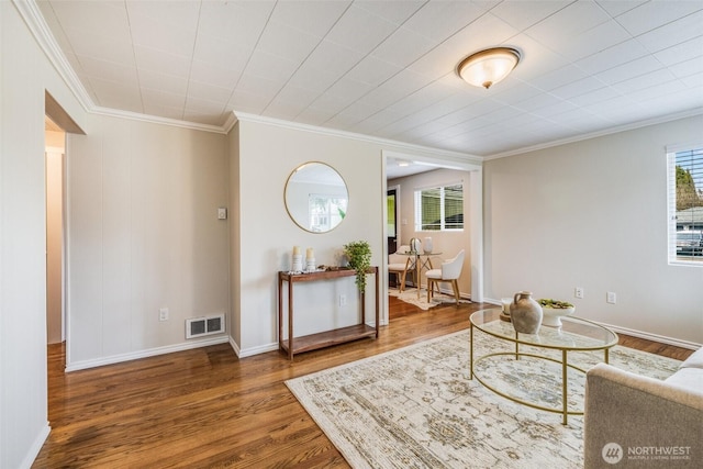 living room featuring visible vents, ornamental molding, baseboards, and wood finished floors