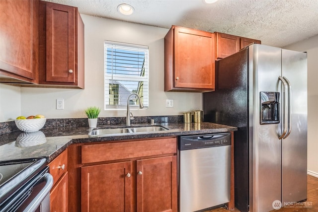 kitchen with brown cabinetry, appliances with stainless steel finishes, a textured ceiling, and a sink