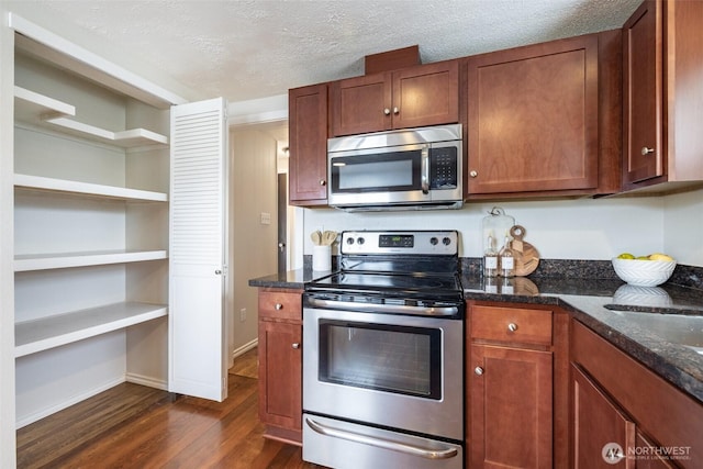 kitchen featuring dark stone countertops, dark wood-style floors, baseboards, stainless steel appliances, and a textured ceiling