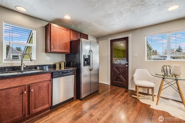 kitchen with recessed lighting, stainless steel appliances, dark wood-style floors, a textured ceiling, and a sink