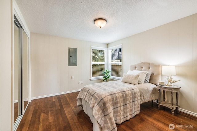 bedroom featuring electric panel, a textured ceiling, baseboards, and dark wood-style flooring