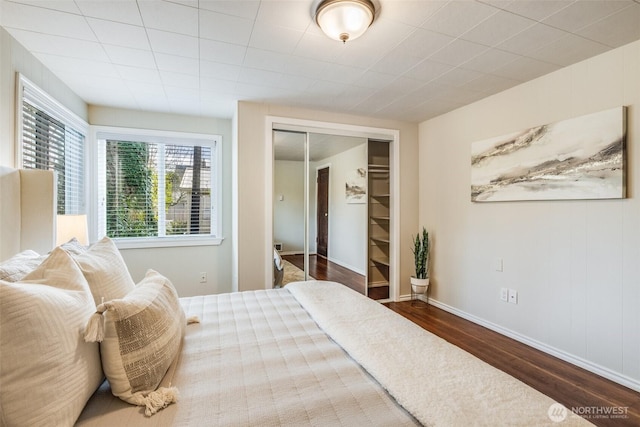 bedroom with wood finished floors, a closet, and baseboards