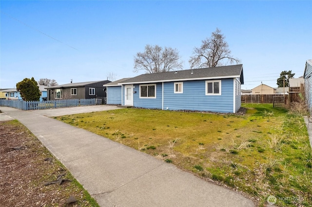 ranch-style house featuring a front lawn and fence