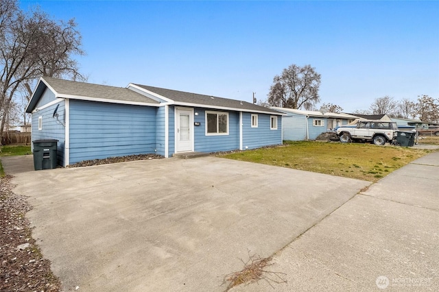 ranch-style home featuring concrete driveway and a front yard