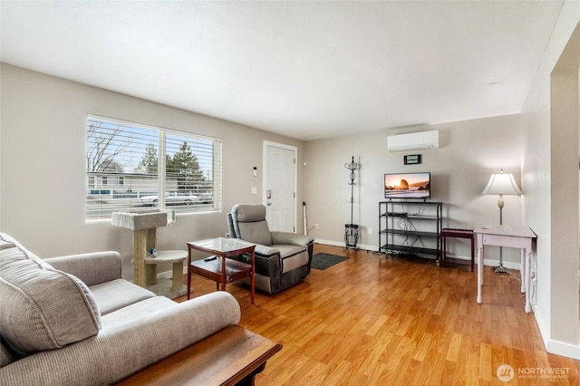 living room featuring light wood finished floors, baseboards, and a wall mounted air conditioner