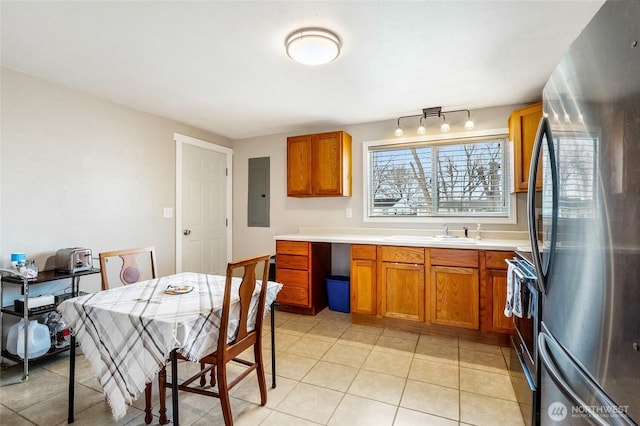 kitchen featuring light countertops, brown cabinets, freestanding refrigerator, and a sink