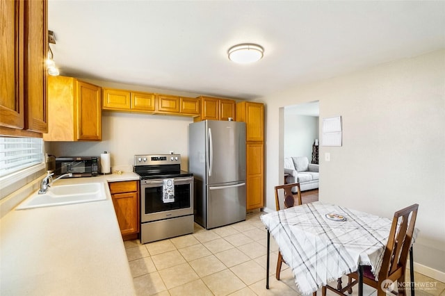 kitchen featuring a sink, appliances with stainless steel finishes, light tile patterned flooring, a toaster, and light countertops