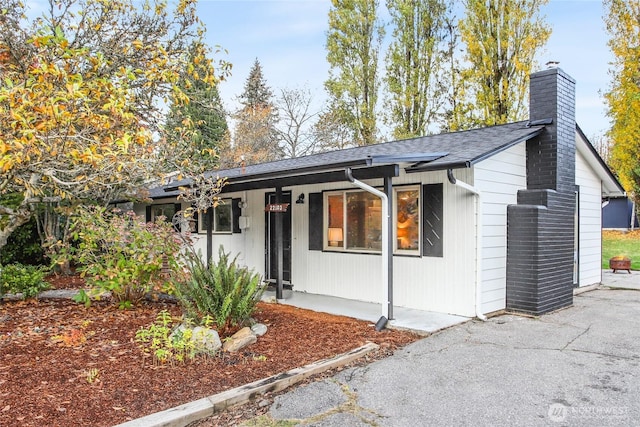 view of front of home featuring a chimney and a shingled roof